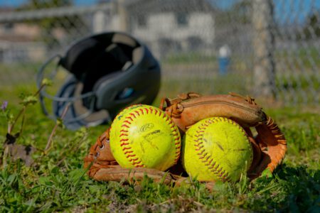 Close-up of baseball gear including balls, glove, and helmet on a field in Houston, TX.